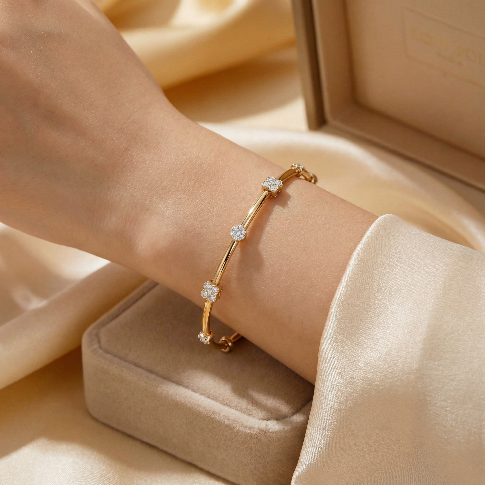Gold bracelet with diamonds on a wrist against a beige fabric background