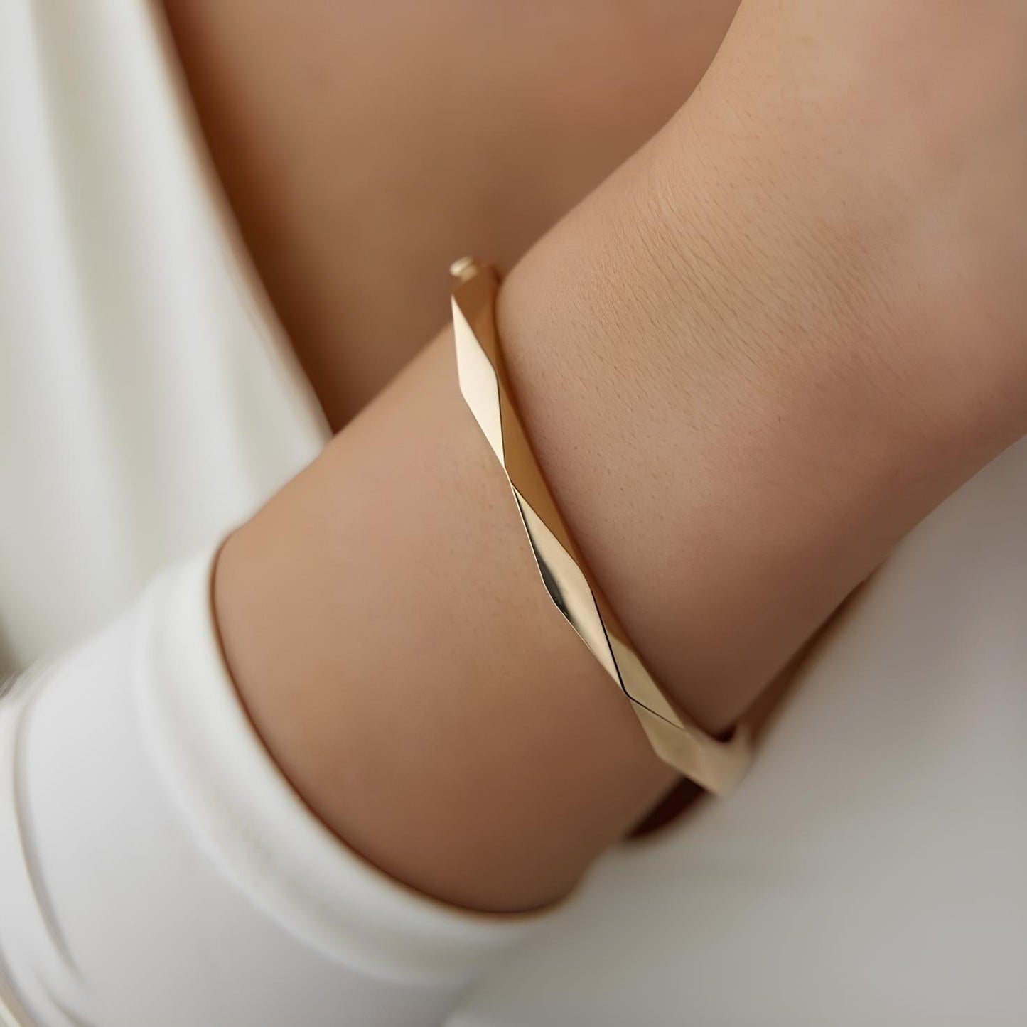 Gold bracelet on a wrist with a neutral background