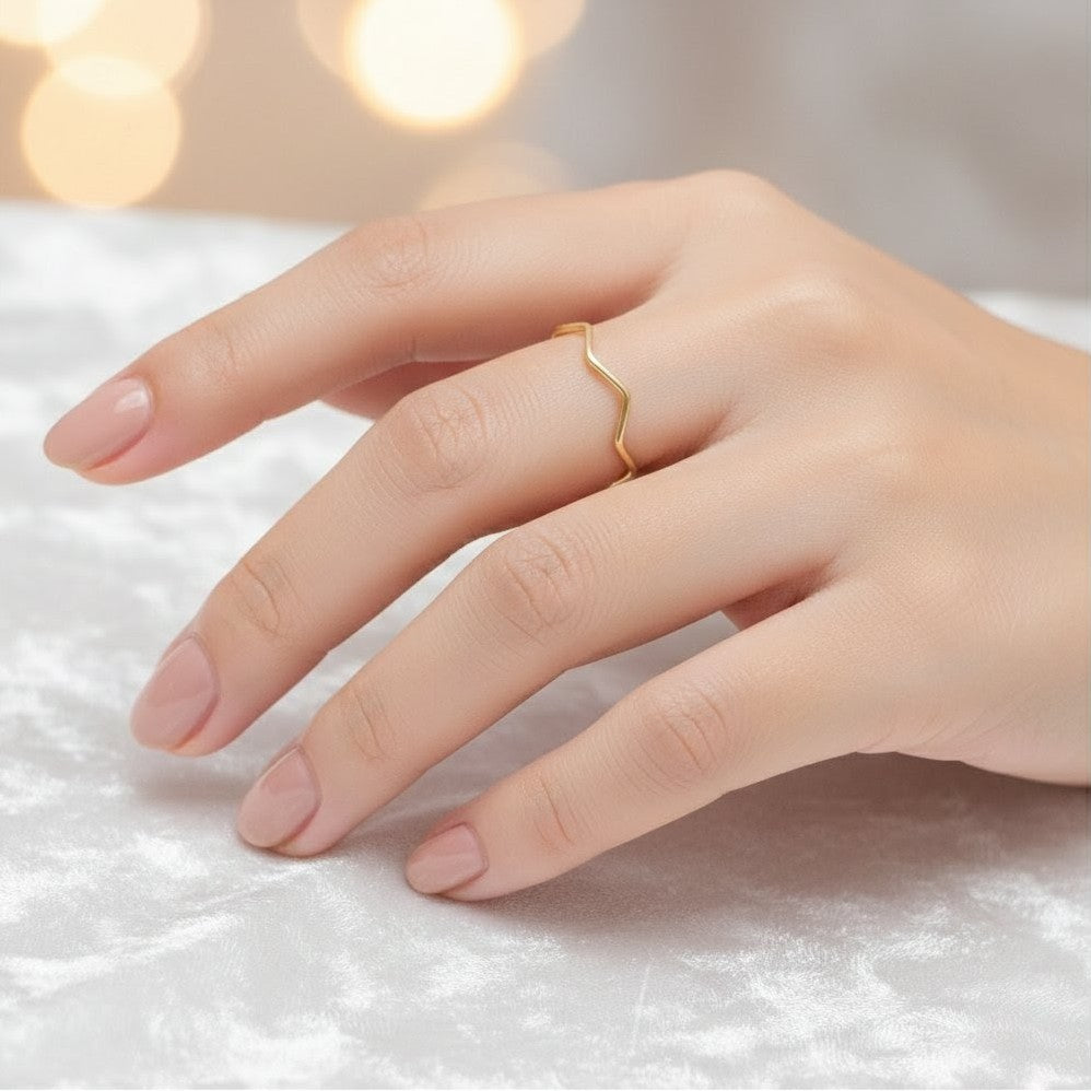 Gold ring on a finger against a soft white background