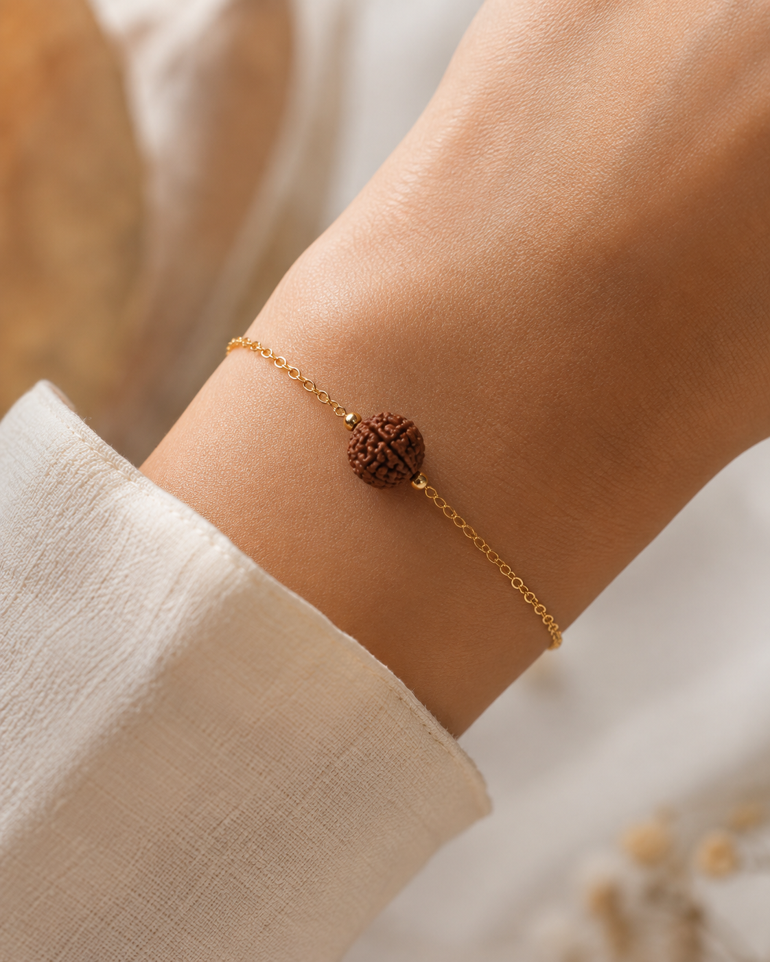 gold chain bracelet with a textured rudraksha, worn on a person's wrist