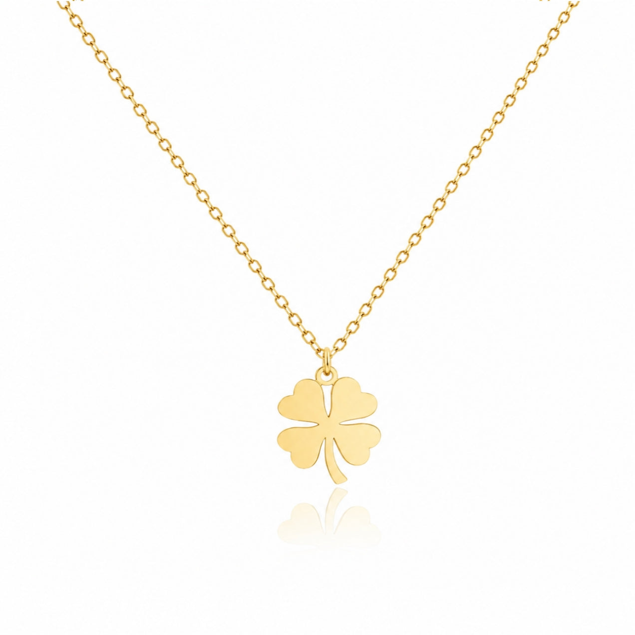A delicate gold chain necklace featuring a polished four-leaf clover pendant, displayed against a clean white background with a subtle reflection below.