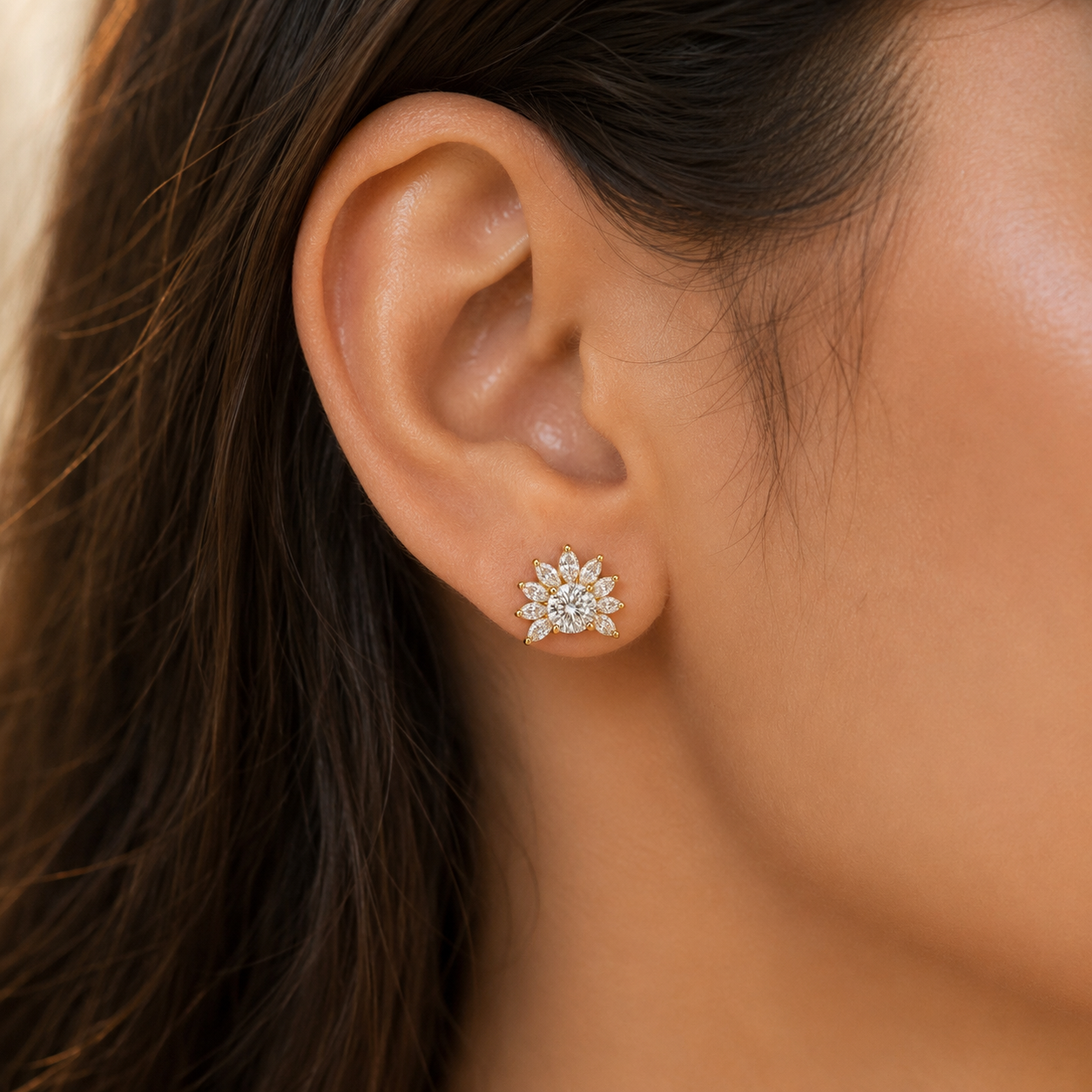 A close-up of a woman's ear wearing a small flower-shaped stud earring with clear stones in a silver-toned setting.